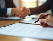 Mains échangeant un contrat signé sur un bureau lumineux